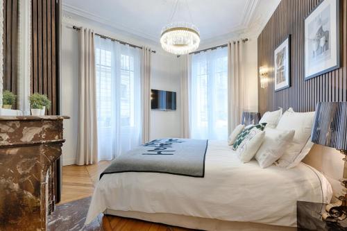 une chambre avec un grand lit et un lustre dans l'établissement Luxury 2-Bedroom for 6 - Avenue Montaigne, à Paris