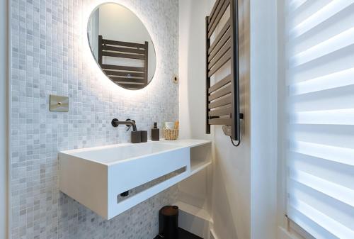une salle de bain avec un lavabo blanc et un miroir dans l'établissement Luxury 2-Bedroom for 6 - Avenue Montaigne, à Paris