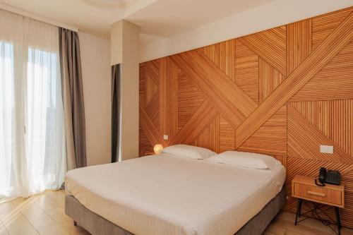 a bedroom with a large bed with a wooden wall at OPHELIA Hotel in Cazzago San Martino