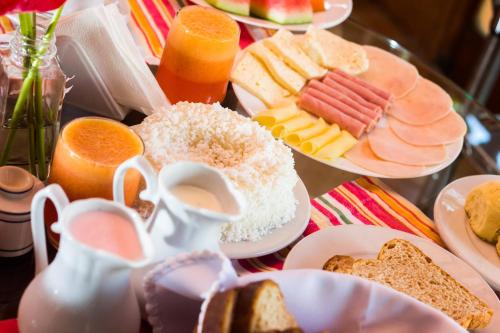 a table topped with plates of breakfast foods and orange juice at Pousada da Mata in Iriri