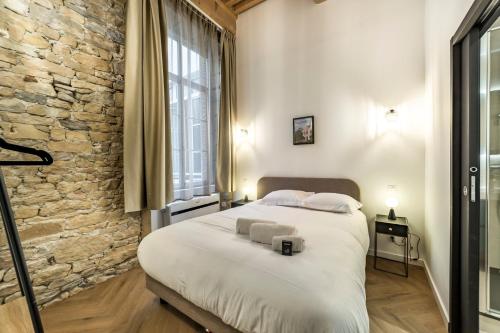 une chambre avec un grand lit et un mur en pierre dans l'établissement Opéra Orchestre, à Lyon