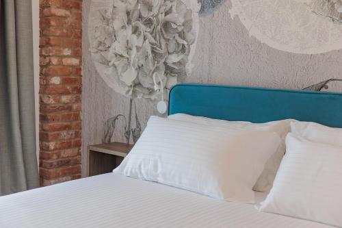 a bed with a blue head board and white pillows at OPHELIA Hotel in Cazzago San Martino