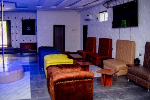 a living room with couches and chairs and a tv at Aloha Hotel & Resort in Oshogbo