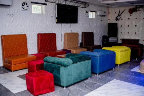 a room with colorful chairs and tables and a television at Aloha Hotel & Resort in Oshogbo