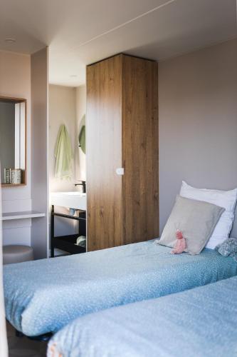 - une chambre avec un lit bleu et une armoire en bois dans l'établissement Camping les Dunes, au Bois-Plage-en-Ré