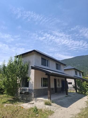 una casa bianca con un portico su un campo di Cabañas Valle Nabú a Lago Puelo