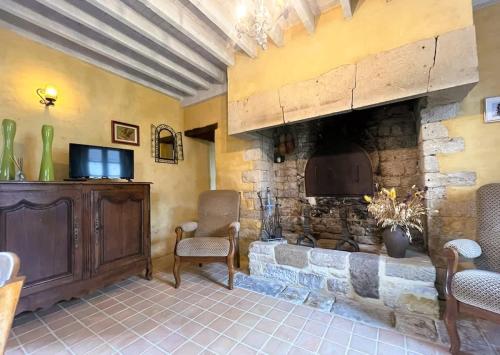 a living room with a stone fireplace and chairs at Le Fournil de Sainte Mère Eglise in Sainte-Mère-Église