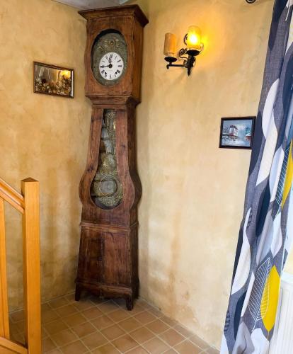 a grandfather clock in the corner of a room at Le Fournil de Sainte Mère Eglise in Sainte-Mère-Église