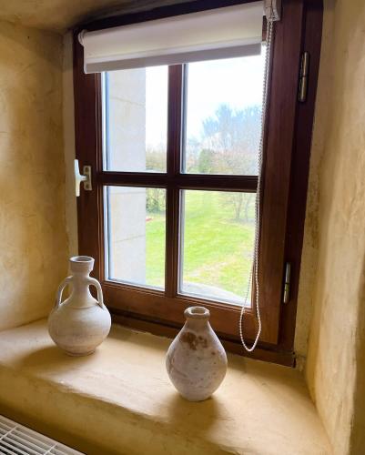 two vases sitting on a window sill in front of a window at Le Fournil de Sainte Mère Eglise in Sainte-Mère-Église