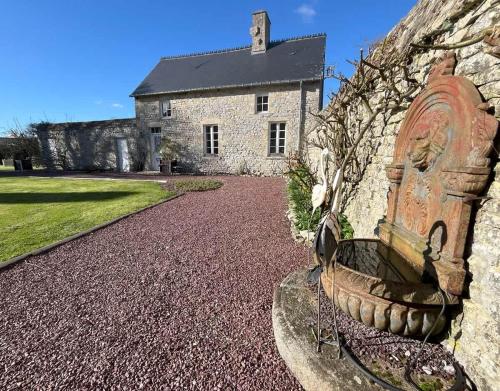 a stone wall with a bench in front of a building at Le Fournil de Sainte Mère Eglise in Sainte-Mère-Église
