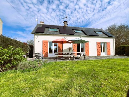une maison avec une table et deux parasols dans la cour dans l'établissement Le Gîte de LiliRose, à Cricqueville-en-Bessin