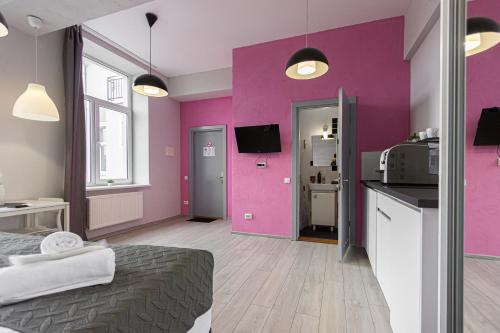 a room with pink walls and a bed and a kitchen at Stories Hub in Lviv