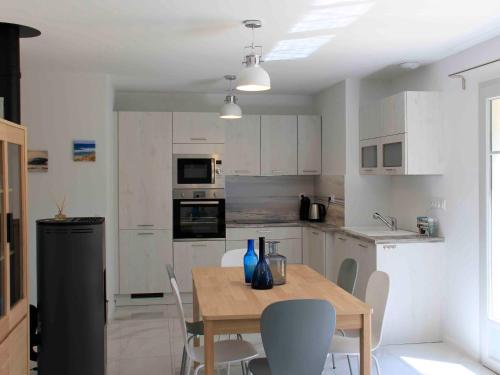 une cuisine avec des placards blancs et une table en bois avec des chaises dans l'établissement Maison charmante à Mimizan Plage pour 5 pers, proche océan et commerces - FR-1-50-115, à Mimizan
