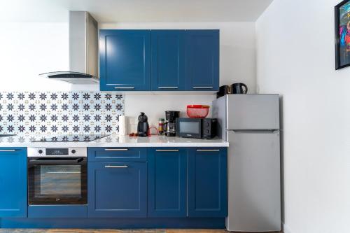 La cuisine est équipée de placards bleus et d'un réfrigérateur blanc. dans l'établissement Appart rénové 3 personnes Proche Citadelle, à Besançon