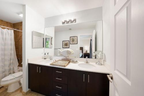 Un baño con lavabo, inodoro y espejo. en Santa Barbara Villa, en Pompano Beach