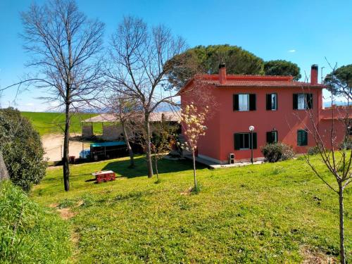 a red house on top of a grassy hill at AltraTerra Casa Rurale in Colle Santa Colomba