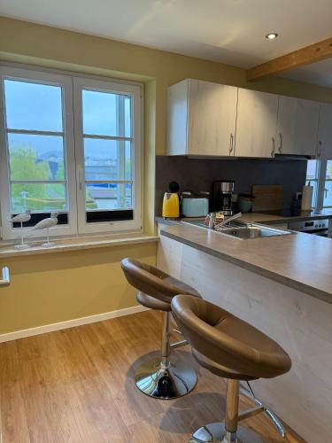 a kitchen with a counter and two bar stools at Villa19hundert5 moderne Ferienwohnungen in zentraler Lage in Lindenberg im Allgäu