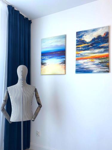 a mannequin in a room with three paintings on the wall at Sun Towers - Apartamenty Bryza - Apartamenty z parkingiem in Świnoujście