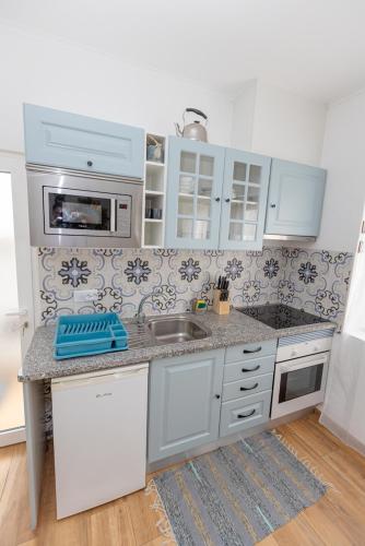 a kitchen with white cabinets and a sink at O Quintal Guesthouse in Carvoeiro