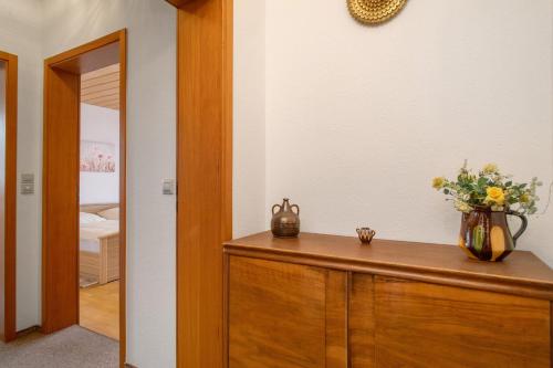 a room with a wooden cabinet with a vase of flowers on it at Hotel Garni Vitamari in Wasserburg am Bodensee