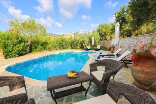 - une piscine avec des chaises en osier et une table à côté dans l'établissement Villa Selini at Sunset Villas, à Skiathos Chora