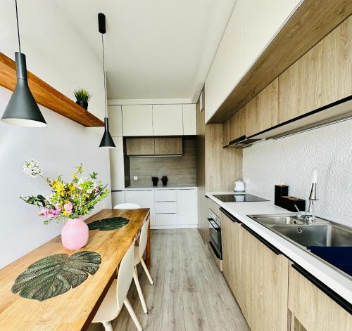 Una cocina con gabinetes blancos y una mesa de madera. en RÓŻANA Poznań free parking, en Poznan