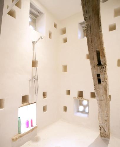 La salle de bains est pourvue d'une douche dans un mur blanc. dans l'établissement Maison de charme - Piscine chauffée - Bouzic, à Bouzic