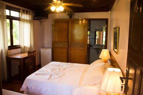 1 dormitorio con 1 cama blanca y ventilador de techo en Pousada da Mata, en Iriri