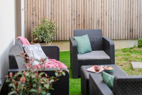 2 chaises en osier et une table basse sur la terrasse dans l'établissement Zephyr by Kleidos- Disney 15min! 3 chambres, 2 terrasses, 2 parkings, 2 salles de bain, à Bussy-Saint-Georges