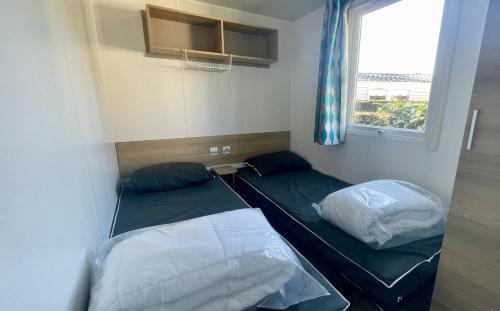 deux lits dans une petite pièce avec une fenêtre dans l'établissement Quiet mobile home - Cc212A Les Charmettes 4 stars, aux Mathes