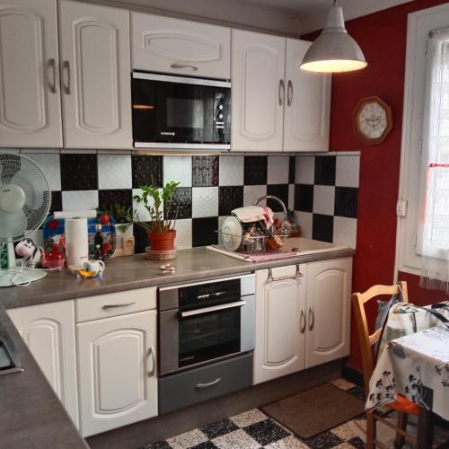 une cuisine avec des armoires blanches et du carrelage noir et blanc dans l'établissement Grand Appartement T2 avec parking et clim à 50m de la Plage centrale !, à Canet