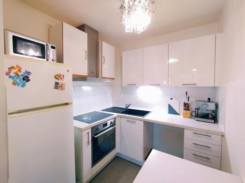 une cuisine avec des armoires blanches et un réfrigérateur blanc dans l'établissement Martin's House, à Bayonne