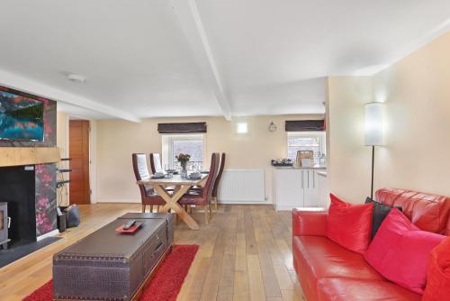 a living room with a red couch and a table at Hayloft Cottage - North East Escapes in Bamburgh
