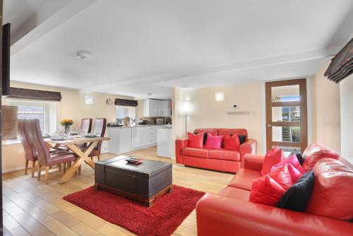 a living room with a red couch and a table at Hayloft Cottage - North East Escapes in Bamburgh