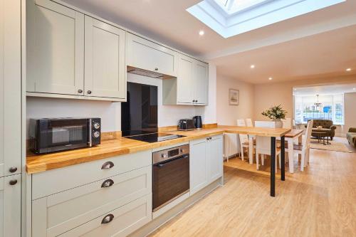 a kitchen with white cabinets and a table with a microwave at Host & Stay - Ginger Bread Cottage in Stokesley