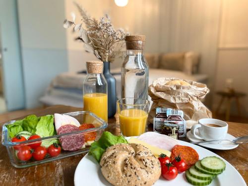 a table with a plate of food and bottles of orange juice at Gellerico Apartments Deák Square in Budapest