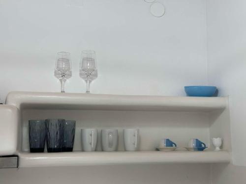 two wine glasses and vases sitting on a shelf at Studios Betty in Plaka Milou