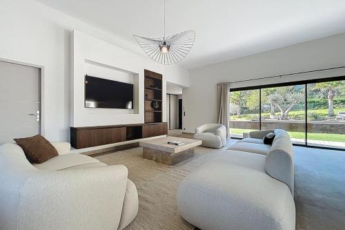 un salon avec deux canapés et une télévision à écran plat dans l'établissement Villa Pineda - Luxe Piscine & Nature, à Lézignan-Corbières