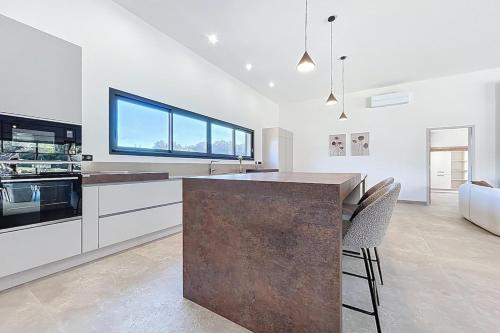 une cuisine avec un comptoir et une grande fenêtre dans l'établissement Villa Pineda - Luxe Piscine & Nature, à Lézignan-Corbières