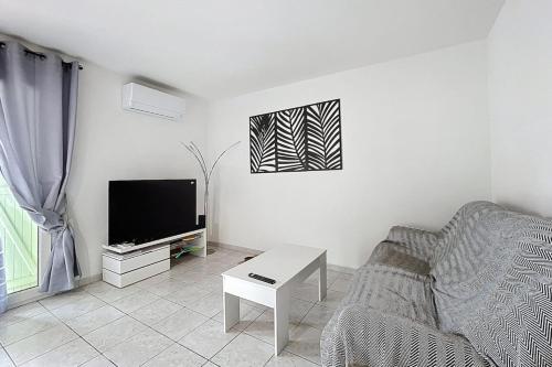un salon avec un canapé et une télévision dans l'établissement La Dali - Maison de vacance proche de la mer, à Sigean