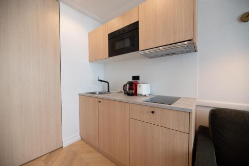 - une cuisine avec des placards en bois et un four micro-ondes dans l'établissement Relax in Paris XII, à Paris