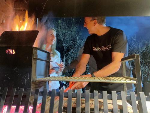 a man cooking food on top of a grill at The Baobab Bush Lodge and Villa in Hoedspruit