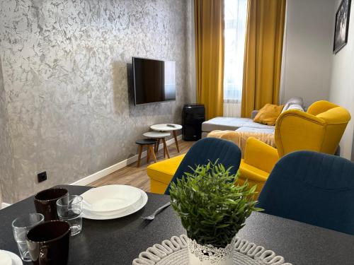 a living room with a table and yellow chairs at Tabago Studio 32 Brzeg Wolności in Brzeg