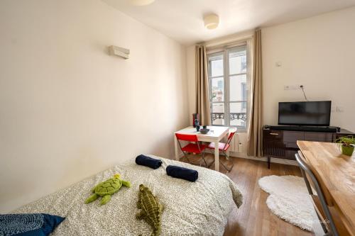 Cette chambre comprend un lit, une table et une télévision. dans l'établissement Cosy Studio - 5mn to Paris, à Bagnolet
