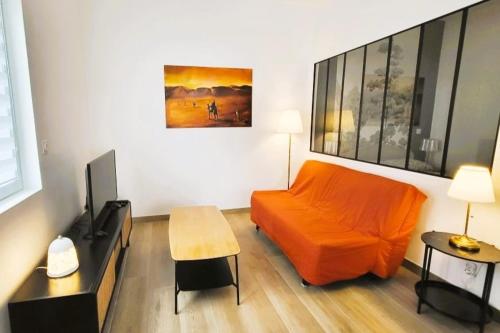 un salon avec un canapé orange et une table dans l'établissement Ravissant T2, proche centre, quartier très calme,,parking,clim, déco soignée, à Montpellier