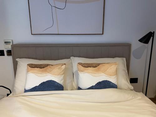 a bed with two pillows and a picture on the wall at Loft by Villa di Piazza - a home you won’t forget in Višnjan