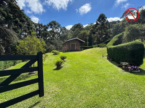 a yard with a fence and a house on a hill at 4 Estações & Chalé da Pedra in Sapucaí-Mirim