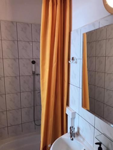 a bathroom with an orange shower curtain and a sink at Leon in Biała Podlaska