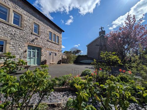 a garden in front of a stone building with a church at Scarside in Ingleton 