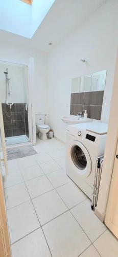une salle de bain blanche avec une machine à laver à l'intérieur dans l'établissement Le Studio du voyageur, Wifi, gare, à Vernon